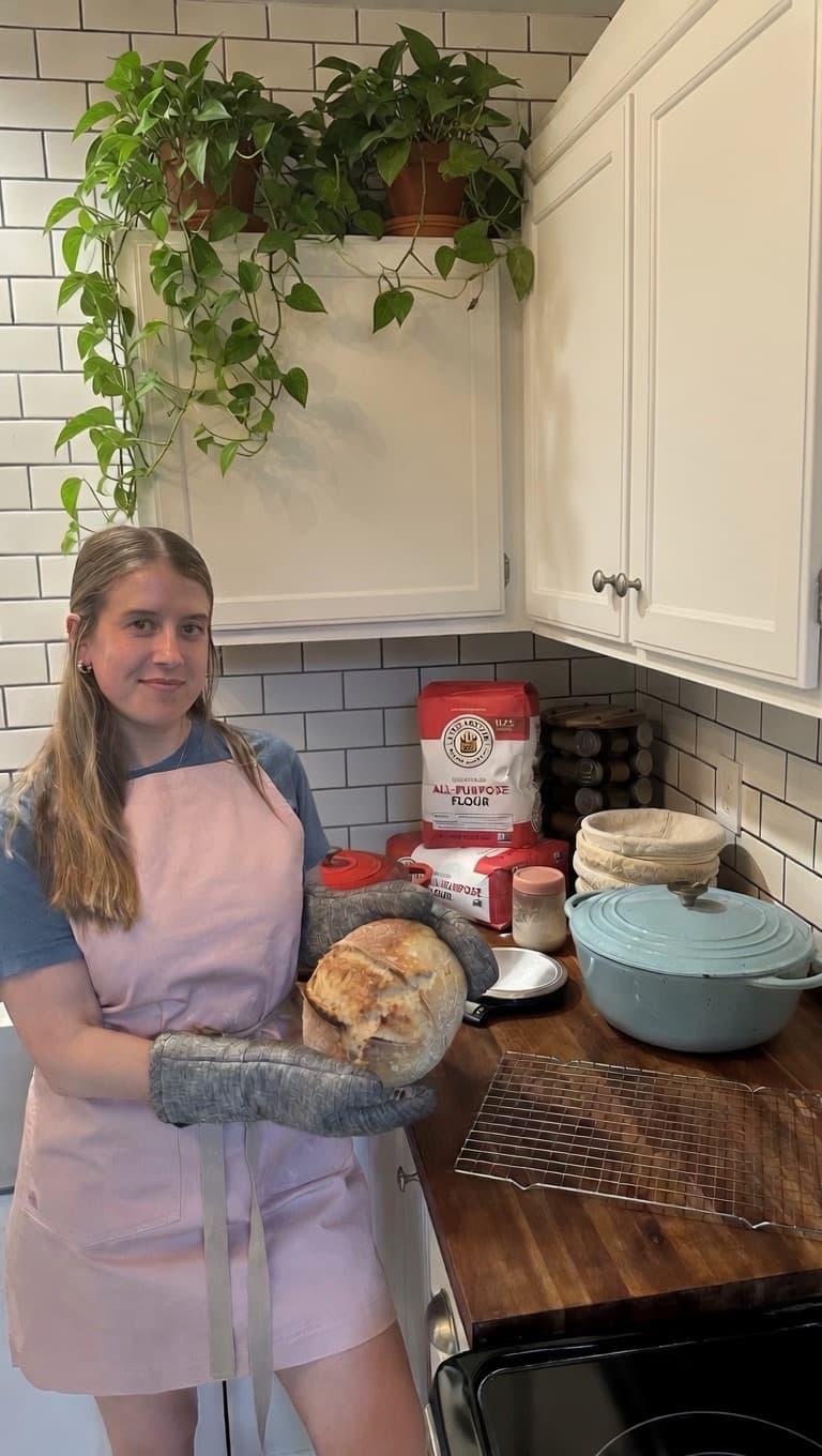 Alexa holding a fresh loaf of sourdough in her kitchen